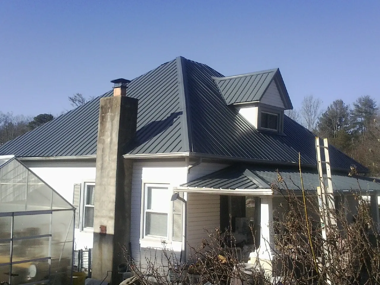 Dark blue standing seam metal roof on a white farmhouse with dormer — Slate & Tile Roof Repair by Roofing Brothers in Centerbrook