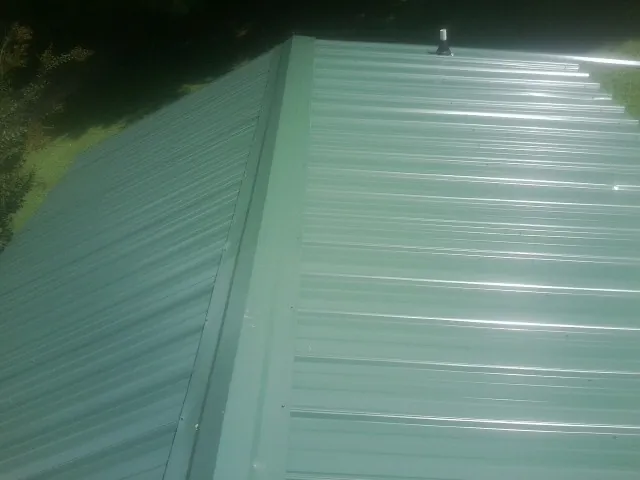 New green metal panels meeting at the ridge of a roof — Flat Roof Repair work by our crew in Centerbrook