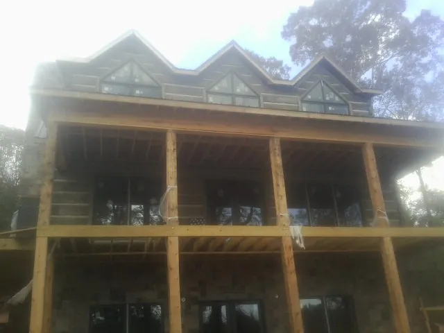 Dormers and porch framing on a large log home under construction — Roof Coating work by our crew in Centerbrook