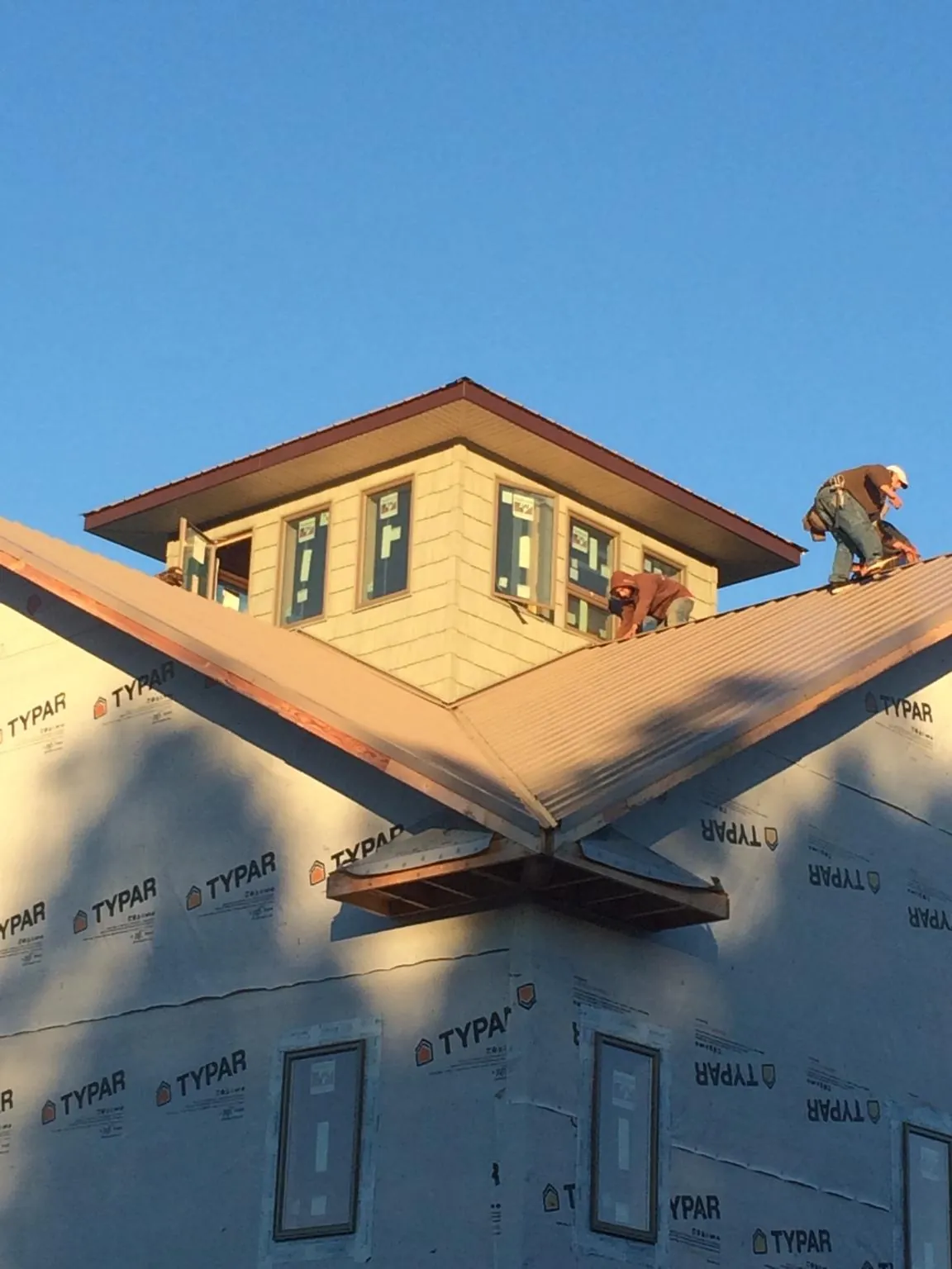 Roofers working around a rooftop cupola on a new metal roof at sunset — Roof Waterproofing in Centerbrook by Roofing Brothers